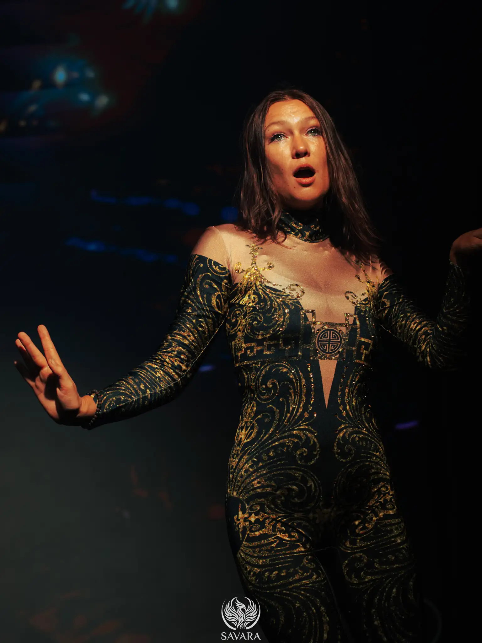 Performer in an ornate black and gold bodysuit on the Savara stage
